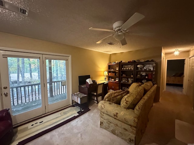 living room with ceiling fan, light colored carpet, and a textured ceiling