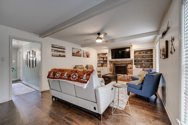 living room featuring ceiling fan, dark hardwood / wood-style flooring, a fireplace, and built in shelves