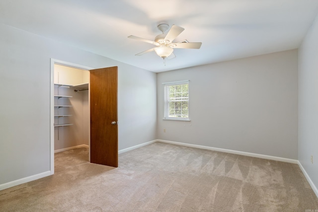 unfurnished bedroom featuring ceiling fan, a closet, light colored carpet, and a spacious closet