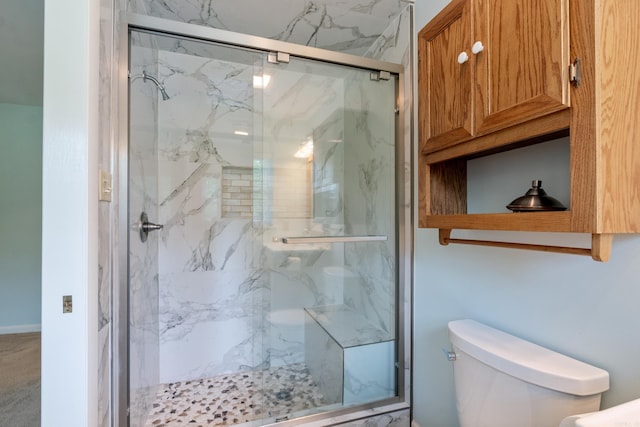 bathroom featuring toilet and a shower with door