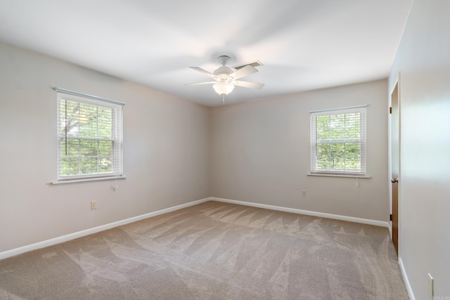 spare room with light colored carpet, a wealth of natural light, and ceiling fan