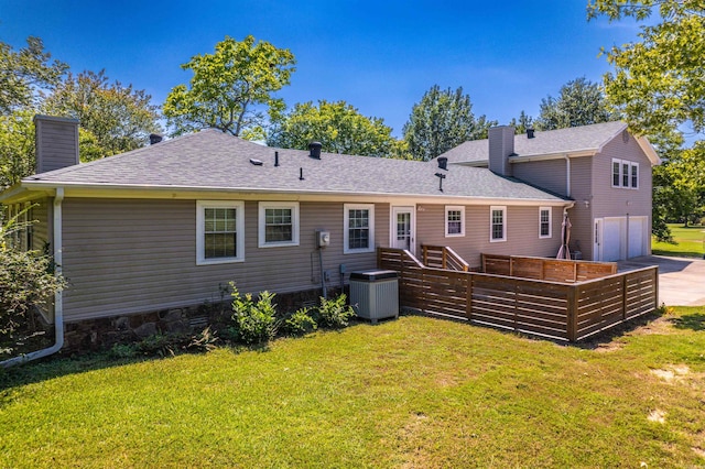 back of house with central AC unit, a garage, and a yard