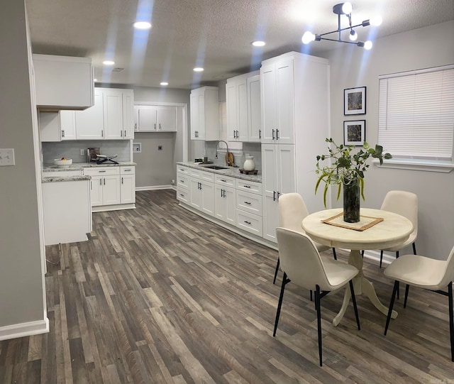 kitchen featuring light stone counters, sink, white cabinets, and dark wood-type flooring