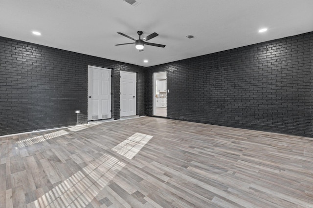 spare room featuring ceiling fan, light hardwood / wood-style flooring, and brick wall