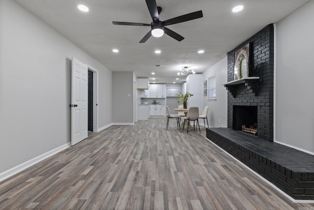 living room featuring ceiling fan, a fireplace, and light hardwood / wood-style floors