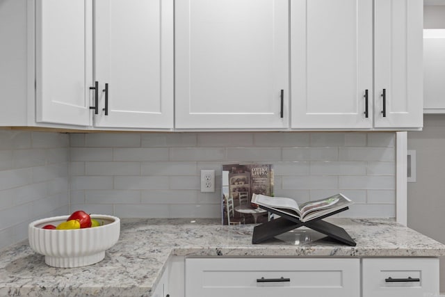 kitchen featuring backsplash, white cabinetry, and light stone counters