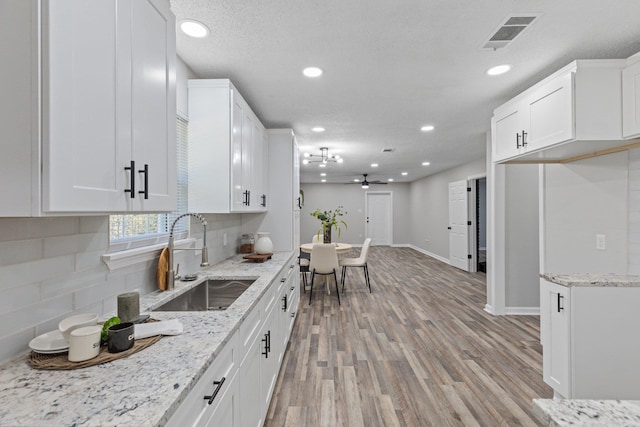 kitchen featuring ceiling fan, white cabinetry, sink, and light hardwood / wood-style flooring