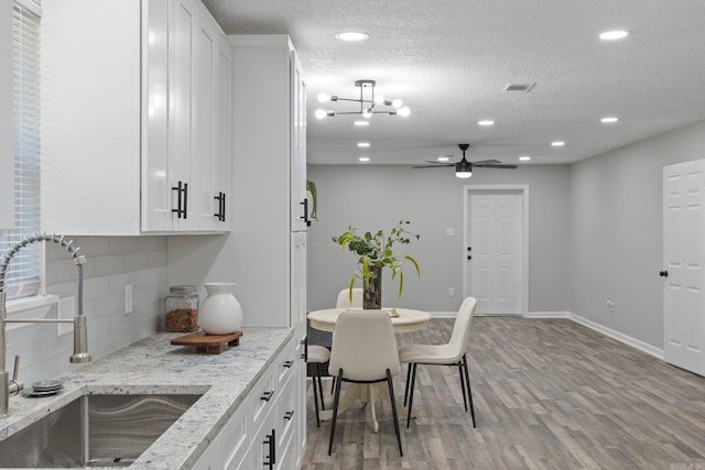 kitchen featuring light stone counters, sink, white cabinets, and light hardwood / wood-style flooring