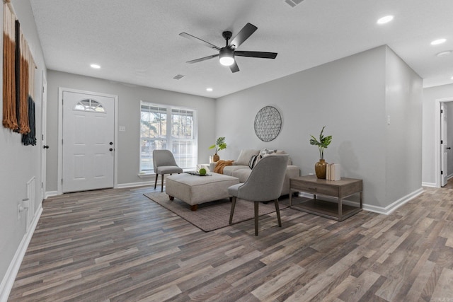 living room with ceiling fan, dark wood-type flooring, and a textured ceiling