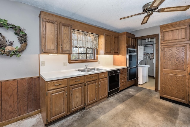 kitchen with wood walls, sink, black appliances, and a textured ceiling