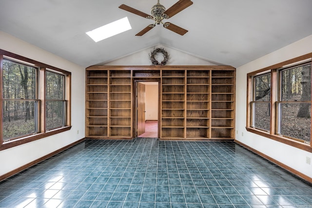 interior space featuring vaulted ceiling with skylight, plenty of natural light, ceiling fan, and dark tile patterned floors