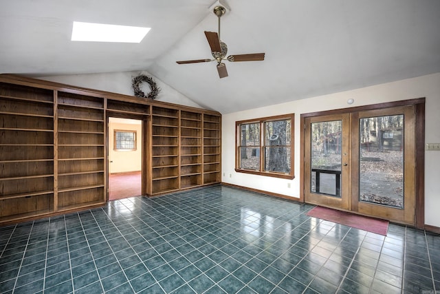 unfurnished room featuring ceiling fan, vaulted ceiling with skylight, and french doors