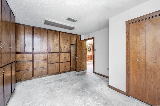 unfurnished bedroom featuring a textured ceiling, wooden walls, and a closet