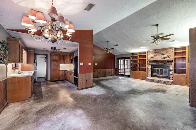 unfurnished living room with vaulted ceiling, wood walls, a textured ceiling, and a brick fireplace