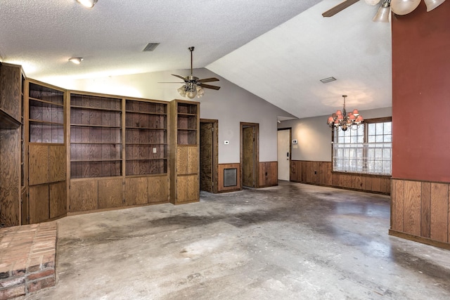 unfurnished living room with ceiling fan with notable chandelier, wood walls, lofted ceiling, and a textured ceiling