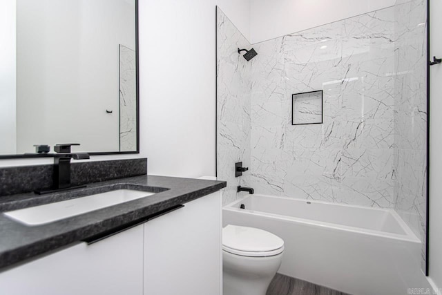 full bathroom featuring vanity, tiled shower / bath combo, and toilet