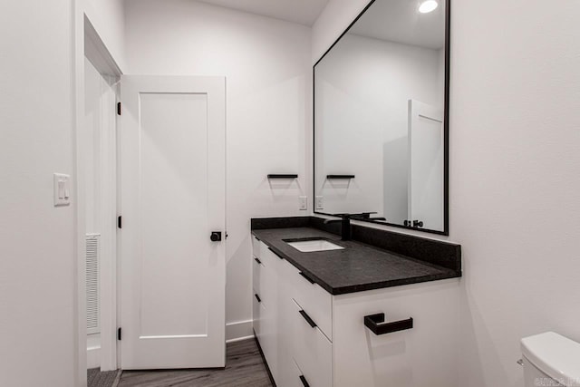 bathroom featuring hardwood / wood-style flooring, vanity, and toilet