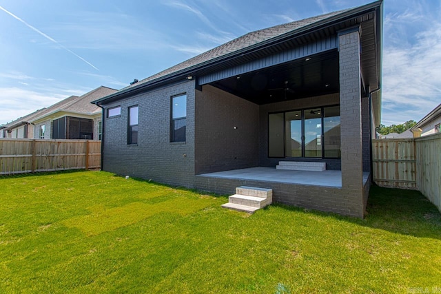 rear view of house featuring a lawn and a patio