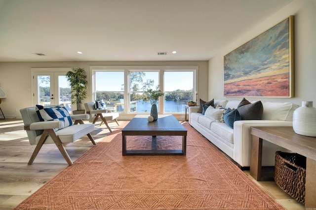 living room with french doors, a water view, and wood-type flooring