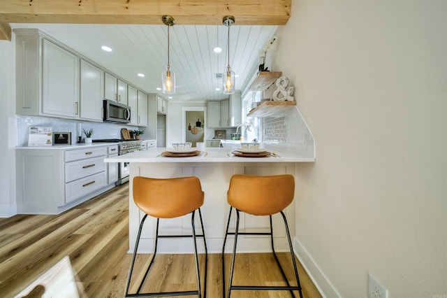 kitchen featuring a breakfast bar, light wood-type flooring, kitchen peninsula, stainless steel appliances, and wood ceiling