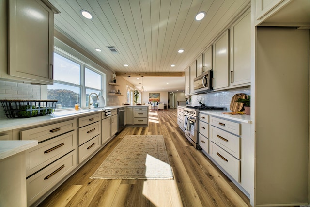 kitchen featuring kitchen peninsula, tasteful backsplash, wood ceiling, stainless steel appliances, and light hardwood / wood-style flooring