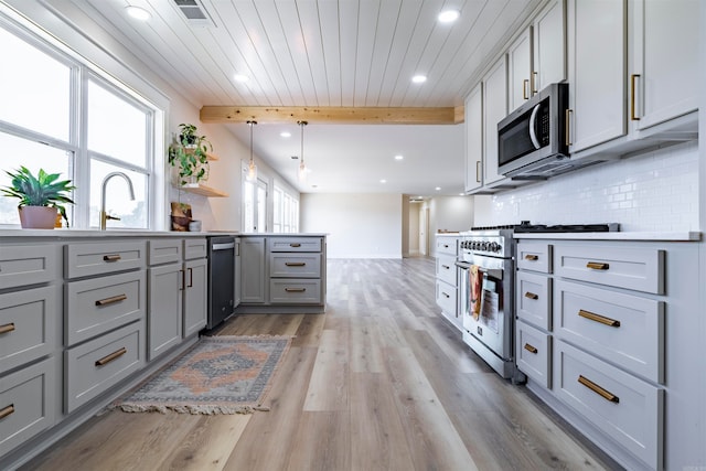 kitchen featuring gray cabinets, pendant lighting, stainless steel appliances, and light hardwood / wood-style floors