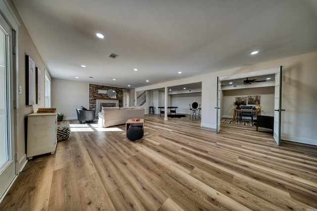 living room with ceiling fan, a fireplace, and light hardwood / wood-style flooring