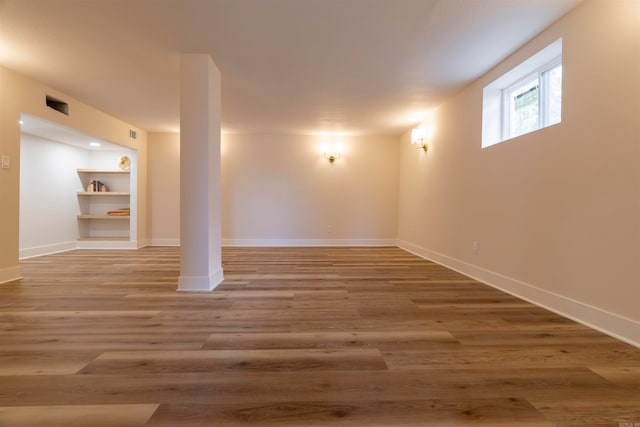 basement featuring hardwood / wood-style flooring and built in shelves