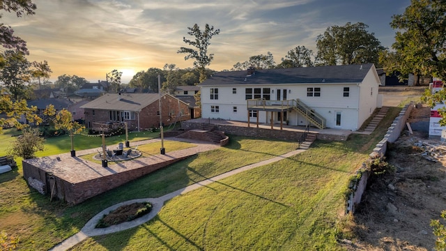 back house at dusk featuring a deck, a yard, and a patio