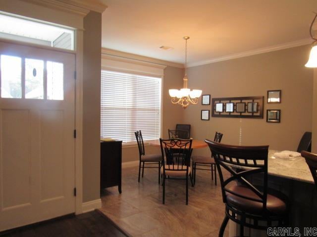 dining area with tile patterned floors, crown molding, and a notable chandelier