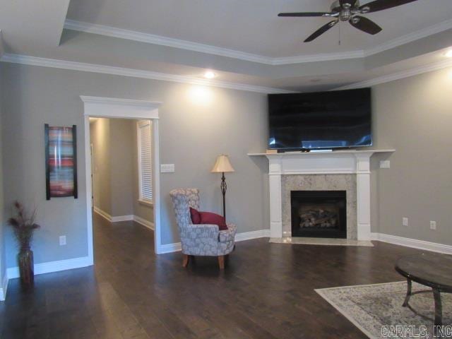 living room with dark hardwood / wood-style floors, ceiling fan, crown molding, and a tray ceiling