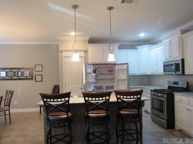 kitchen featuring white cabinetry, hanging light fixtures, stainless steel appliances, crown molding, and a kitchen island with sink