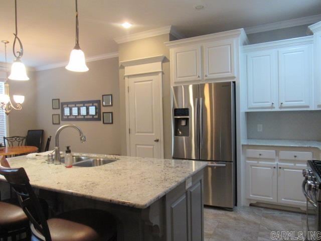 kitchen with light stone counters, stainless steel appliances, sink, decorative light fixtures, and white cabinets