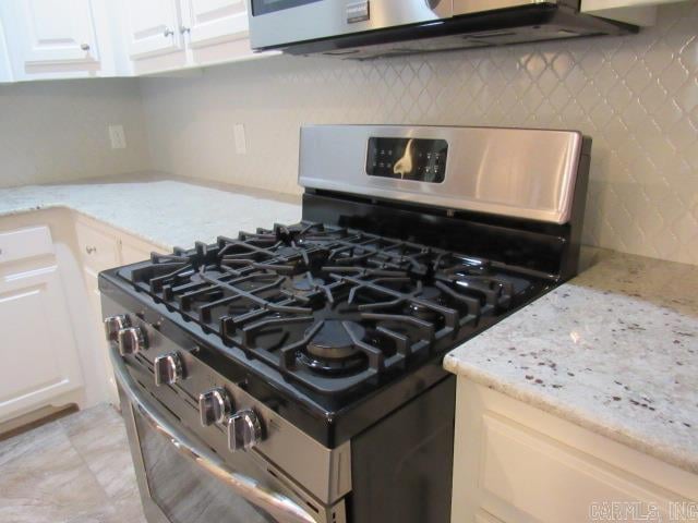 interior details featuring decorative backsplash, light stone counters, and appliances with stainless steel finishes