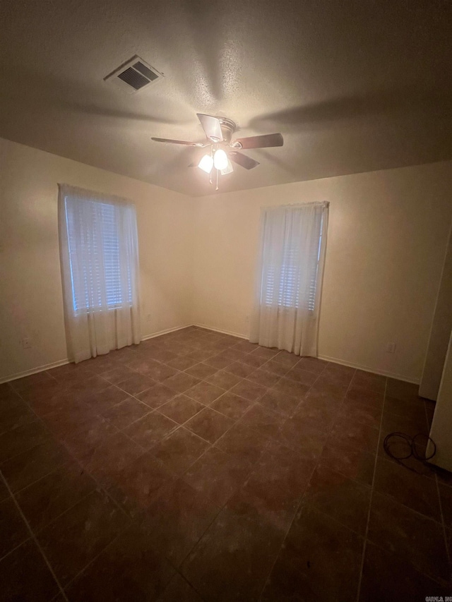 tiled empty room with a textured ceiling and ceiling fan