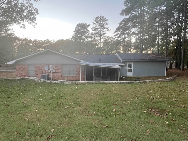 back of property with central air condition unit and a lawn