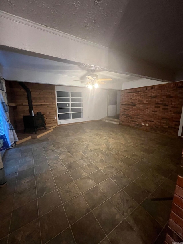 additional living space featuring a wood stove, ceiling fan, built in features, brick wall, and a textured ceiling