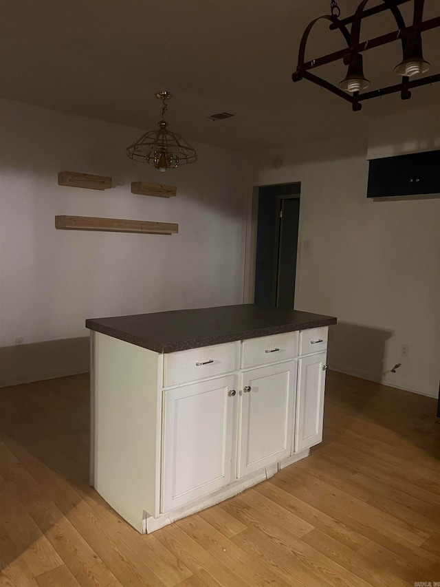 kitchen with light wood-type flooring, white cabinetry, and a kitchen island