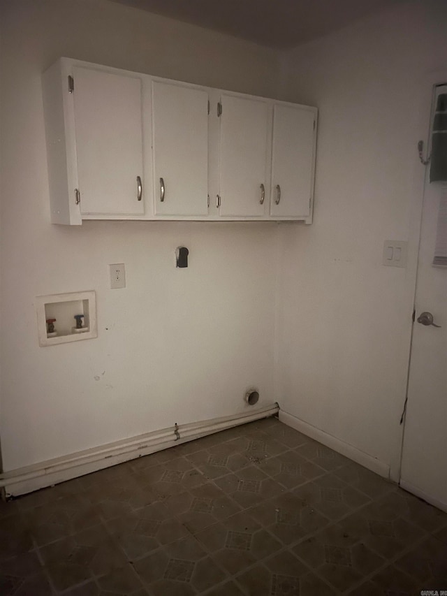 washroom with hookup for a washing machine, dark tile patterned floors, and cabinets