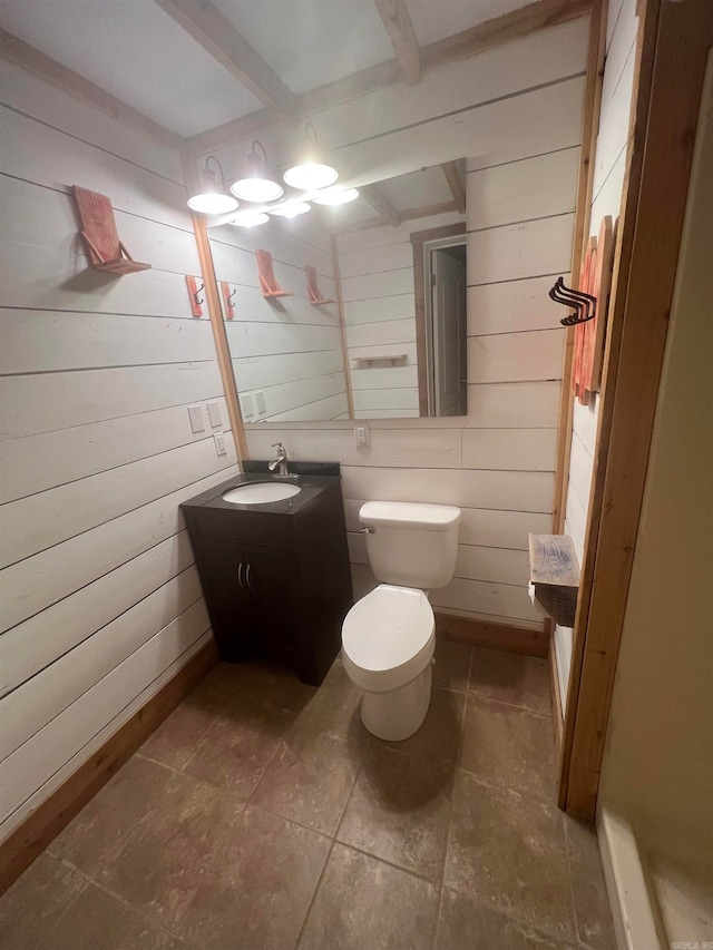 bathroom with beam ceiling, wood walls, vanity, and toilet