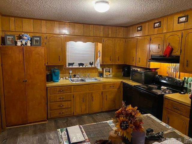 kitchen with sink, dark wood-type flooring, a textured ceiling, and black appliances