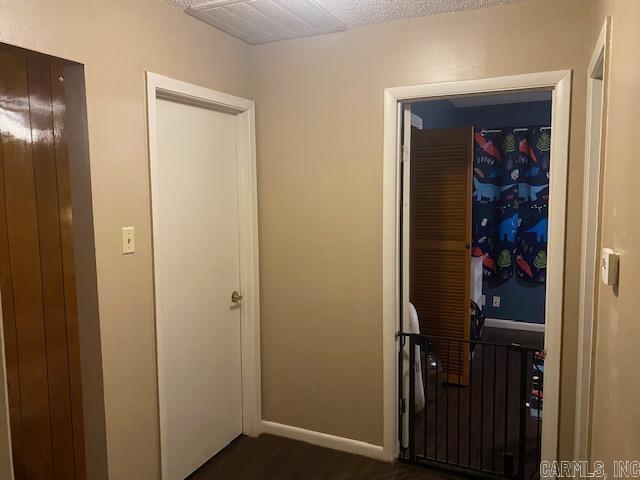 corridor with dark hardwood / wood-style floors and a textured ceiling