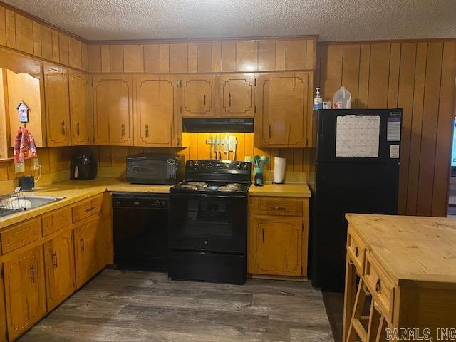 kitchen with dark wood-type flooring, sink, a textured ceiling, and black appliances