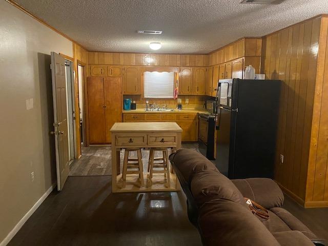 kitchen featuring sink, dark wood-type flooring, dishwasher, black refrigerator, and a textured ceiling