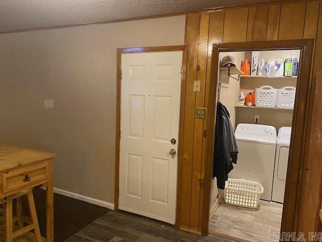 laundry area with washing machine and dryer, a textured ceiling, and wood walls