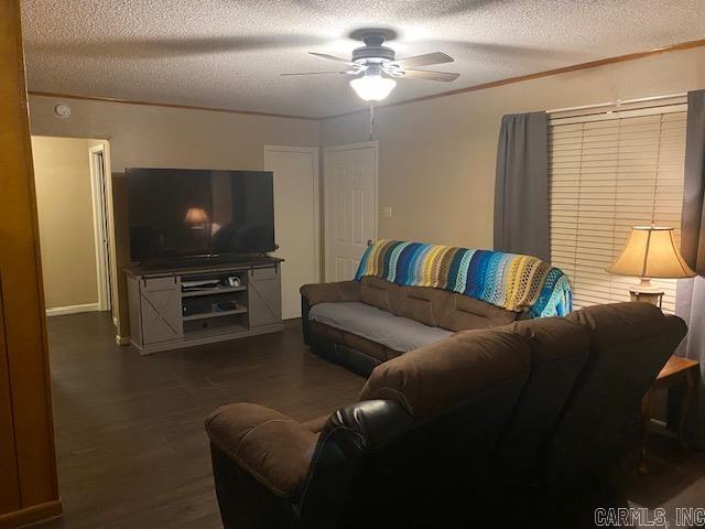 living room with ceiling fan, dark wood-type flooring, and a textured ceiling