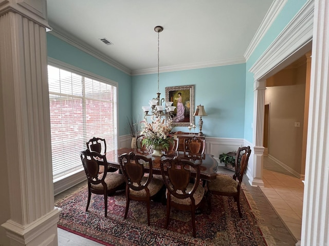 tiled dining room featuring decorative columns, an inviting chandelier, and crown molding