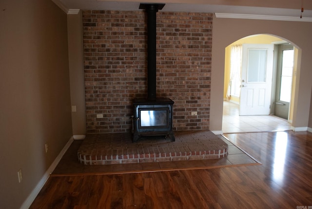 unfurnished living room with wood-type flooring, crown molding, and a wood stove