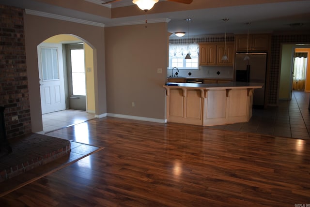 kitchen featuring sink, dark wood-type flooring, crown molding, decorative light fixtures, and appliances with stainless steel finishes