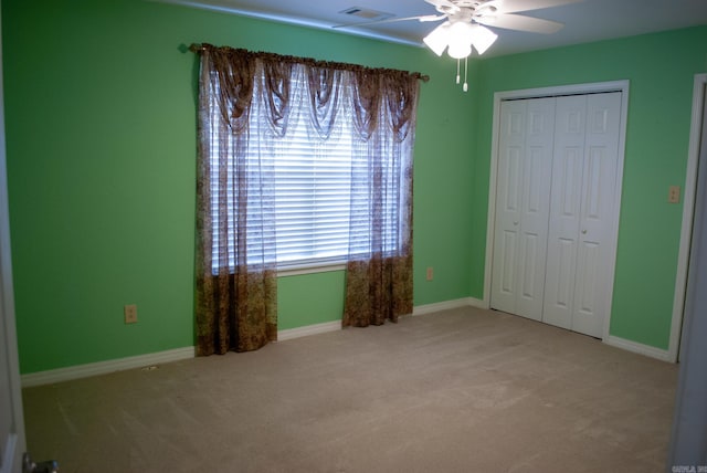 unfurnished bedroom featuring ceiling fan, light carpet, and a closet